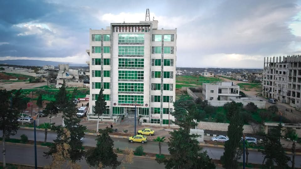 مبنى مشفى إيبلا التخصصي من الخارج، مبنى من عدة طوابق بواجهة زجاجية خضراء على الطريق